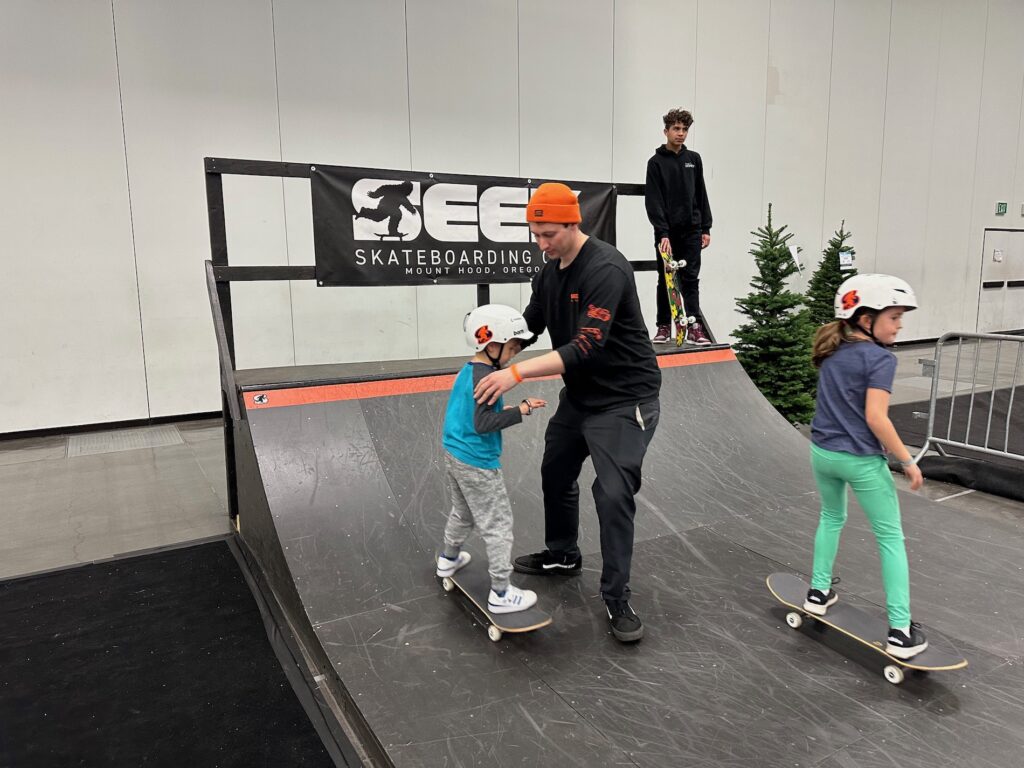 a instructor teaching skateboarding to two kids in the halfpipe at Snowvana 